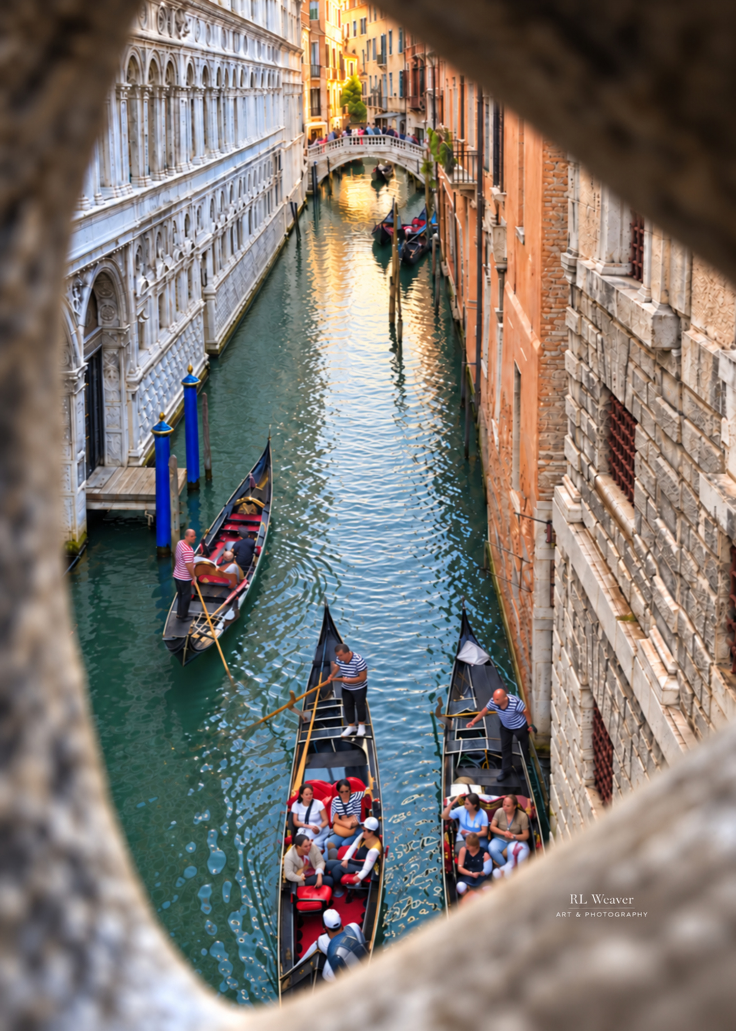 Gondolas on a Venice canal, viewed from above through a gap in a stone bridge